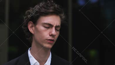 Young businessman near office building, feeling bad, sad and annoyed. man tired and having problems, putting hands to