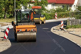 Two special autos paving new asphalt driving in line one near another