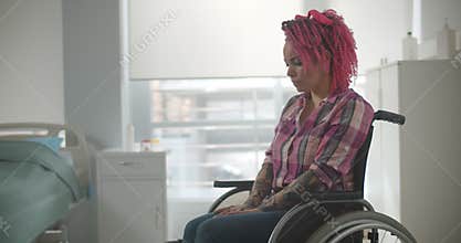 Sad young woman patient in hospital sitting in wheelchair