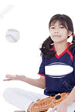Girl throwing softball up in air while sitting