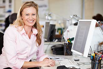 Woman Working At Desk In Busy Creative Office
