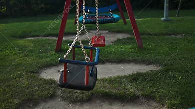 Children&#x27;s swings hang empty an idle at a playground on a dull.