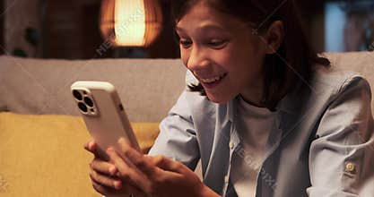Boy Expressing Amazement While Using Phone on the Sofa in the Evening