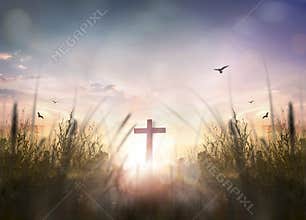 The wooden cross on meadow on sunrise background