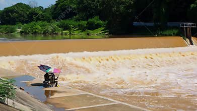 Two men are fishing in turbulent muddy water.