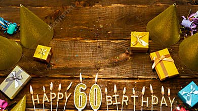 Happy birthday 60. Top view of the golden letters of the candle with the number happy birthday, the background of the gift boxes