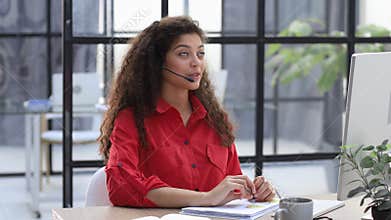 Call operator in red shirt wears headset customer service manager looking to webcam, communicating in distance remote