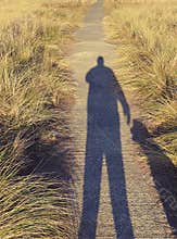 Dog owner walker and their pet dog shadow on a walk for exercise