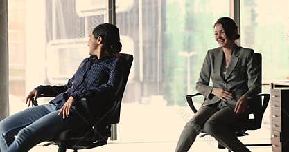 Two women colleagues have fun spend break riding on chairs