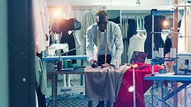 African-american dressmaker is cutting fabric in his studio