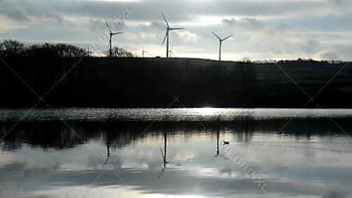 Video silhouette of wind farm with turning wind turbines reflected in lake