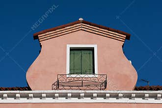 View of an atique window in an Italian house in Burano, Italy against a clear blue sky background