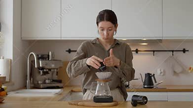 Shot of woman make delicious drip coffee at home in bright white kitchen. Perfect for coffee or home-related content