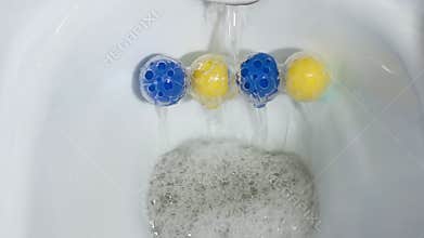 Close-up of an antiseptic against fungus remedy. Top view flush toilet bowl with water. Scented balls for the toilet.