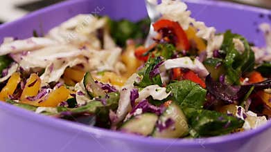 Healthy food concept arugula or salad mix with vegetables. Close-up with a fork to eat fresh salad at home or in a restaurant.