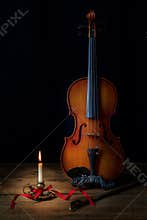 Violin and Burning Candle in Dark Room