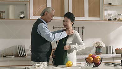 caring senior asian man putting on apron for wife