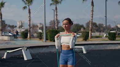 Woman making shoulder workout with rubber bands. Be H3althy.