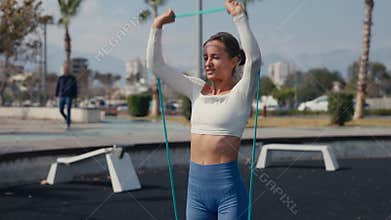 Woman making shoulder workout with rubber bands. Be H3althy.