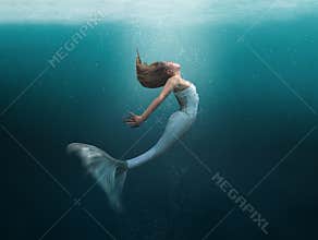 Mermaid in graceful swim undersea with sunlight shinning through the surface onto her beautiful face. Matte painting technique.