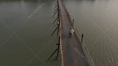 Unique bridge experience with scooters over calm water at sunset