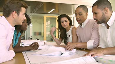 Group Of Architects Discussing Plans In Modern Office