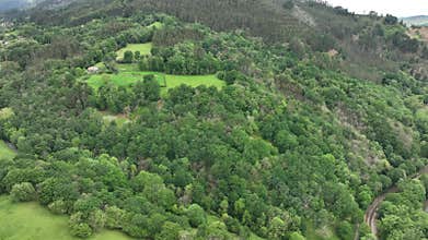 Aerial view of lush countryside with village, forest, and mountains, Infiesto, Asturia, Spain.