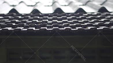 In the countryside, rain is pouring heavily on the roof tiles of the bungalow