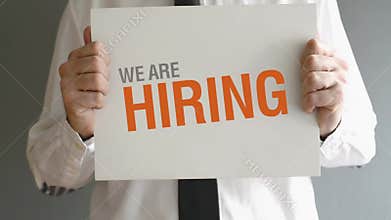 Businessman holding paper board with WE ARE HIRING title.
