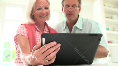 Middle Aged Couple Looking At Digital Tablet