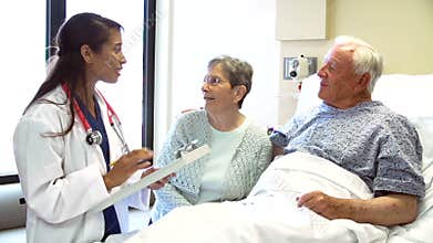 Doctor Talking To Senior Couple In Hospital Room