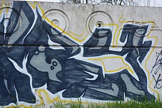 Graffiti depicting the word MAM on white, gray concrete fence.