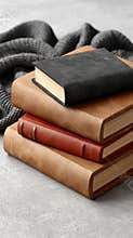 Four hardcover books in vibrant colors are stacked together, showcasing their textures against a gray background
