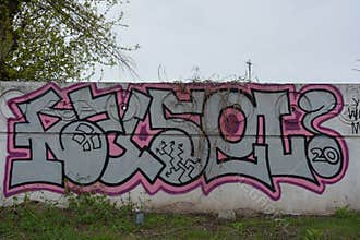 A drawing, graffiti depicting word RUSEL ! is painted on a white-gray concrete fence.