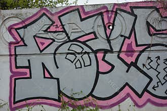A drawing, graffiti depicting word RUSEL ! is painted on a white-gray concrete fence.