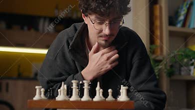 Focused Hispanic guy player playing chess mind game at home hipster look chessboard thinking brainstorm strategy