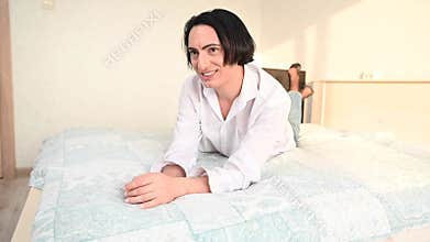 Man flirting with camera while lying on bed.