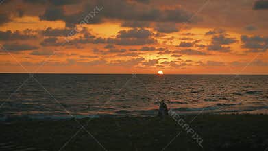 Dark silhouette in backlight. Two women are walking along the seashore. Photograph and model. Warm yellow sunset