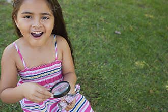 Girl examining a butterfly with magnifying glass at park