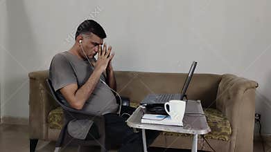 Man Working From Home Appears Overwhelmed Placing Hands on Forehead and Moving Head