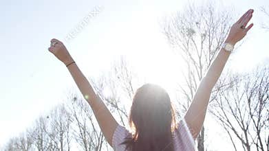 Woman in the outdoors with arms wide open under th