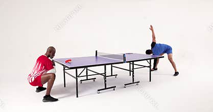 Playing table tennis, two men competing intensely in studio setting