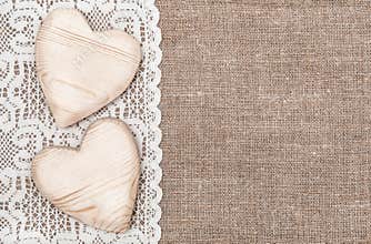 Burlap background with lacy cloth and wooden hearts