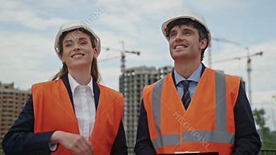 Engineers collaborate building strategy shaking hands at urban worksite closeup.