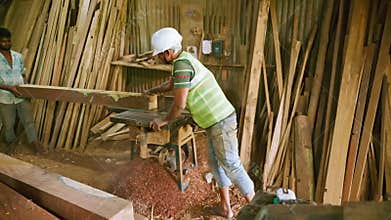 Craftsman builds wooden item with his assistant