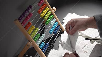 A man counts expenses on a wooden abacus. A man keeps records. A wooden abacus instead of a calculator.