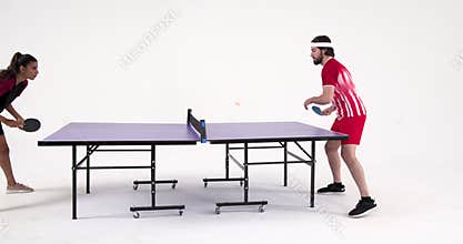 Playing table tennis, man and woman competing in studio match