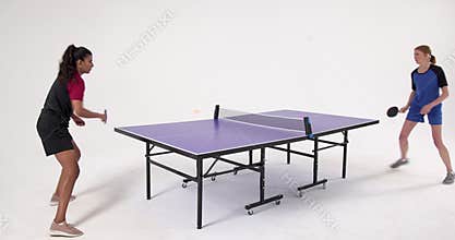 Playing table tennis, two women competing in match with paddles and ball