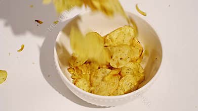 potato chips with spices fall into a bowl.