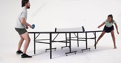 Playing table tennis, man and woman competing in intense match indoors